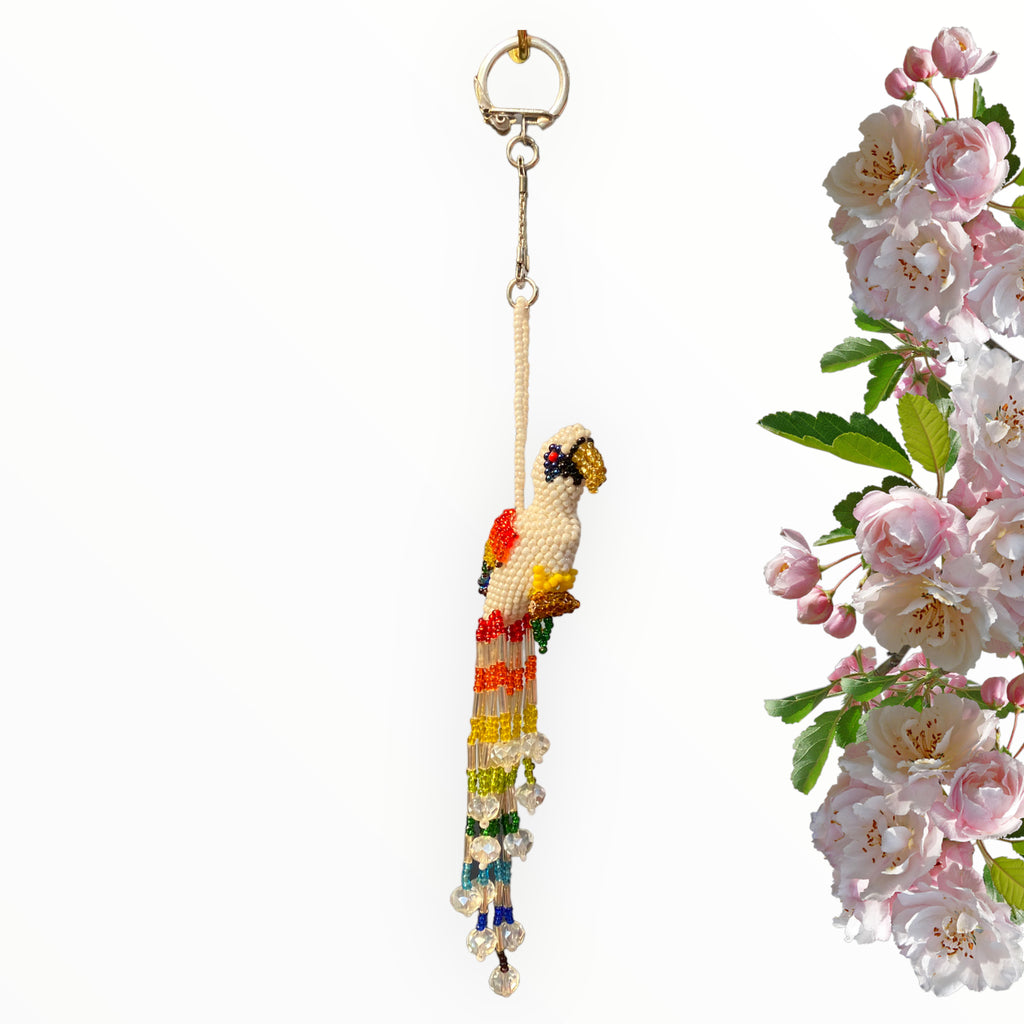 Witness the superb artistry embodied in our white parrot, a stunning masterpiece featuring wings ablaze with tropical hues. The majestic white body and golden beak emanate a sense of joy, while the softly colorful tail, adorned with a fanciful collection of vibrant beads, introduces a playful touch