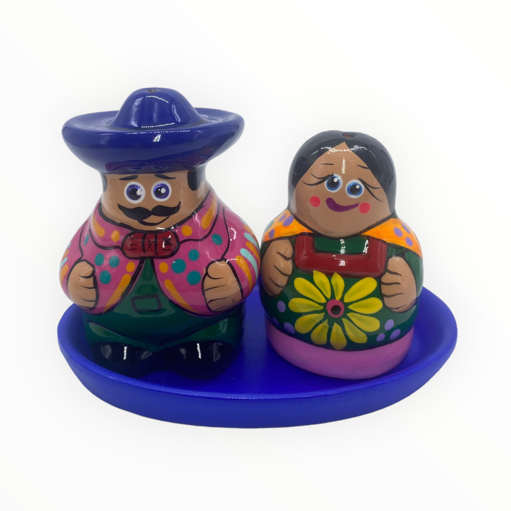 "Immerse yourself in the world of Mexican craftsmanship with this hand-painted salt and pepper shaker set. The gentleman exudes character with his mustache, blue hat, and stylish pink jacket, while the lady radiates charm in her green dress adorned with a delicate floral touch.